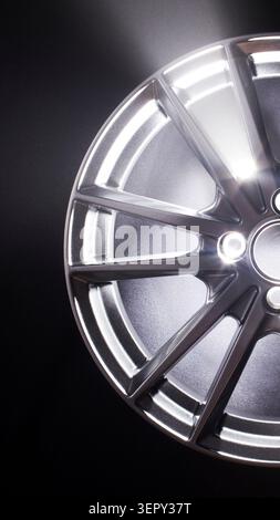 Detailed studio shot of modern alloy car wheel rim showcasing intricate design and glossy finish, light creating striking highlights on metal texture Stock Photo