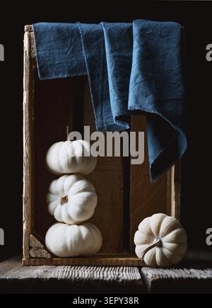 White decorative Baby Boo pumpkins in wooden box with blue napkin close up. Thanksgiving or Halloween food styling in cozy autumn setting Stock Photo