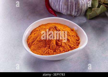 Vibrant orange turmeric powder piled in white ceramic bowl surrounded ...