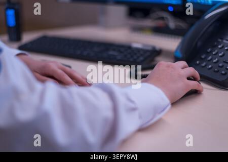 A close-up, shallow depth of field shot focusing on a person's hand wearing light-colored nail polish using a black computer mouse on a light wooden o Stock Photo