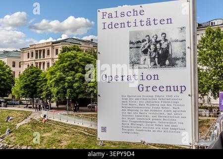 Information board about the Allied covert operation ‘Operation Greenup’ on the Marko-Feingold footbridge. The OSS operation in February 1945 was carried out to gather intelligence behind German lines in Tyrol. Buildings and passers-by can be seen in the background. Salzburg, Austria Stock Photo