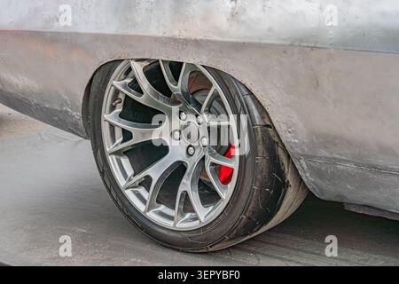 Modern luxury car body detail featuring polished multi-spoke wheel, metallic fender, gray paint finish, performance tire tread pattern, studio lightin Stock Photo