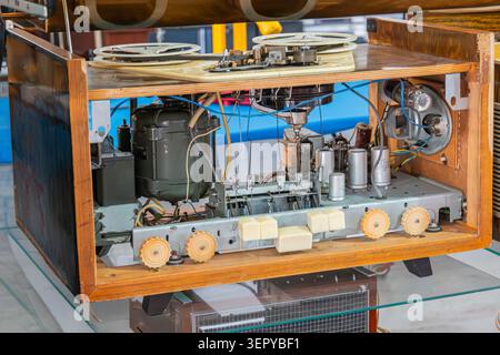 Vintage tape recorder with reel-to-reel mechanism and exposed electrical components showcasing intricate mechanical parts, control panel knobs, and ne Stock Photo
