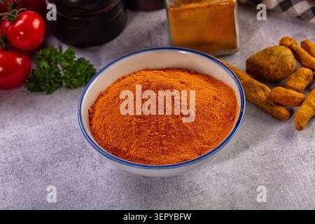 Vibrant orange turmeric powder piled in white ceramic bowl surrounded ...