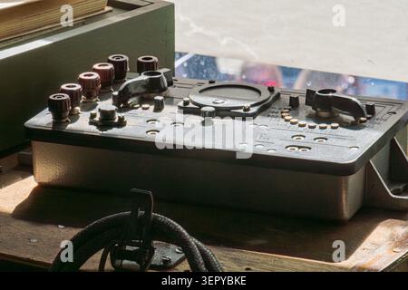 Vintage industrial control panel featuring worn knobs and switches showcasing robust metal construction and weathered wooden mount emphasizing rugged Stock Photo