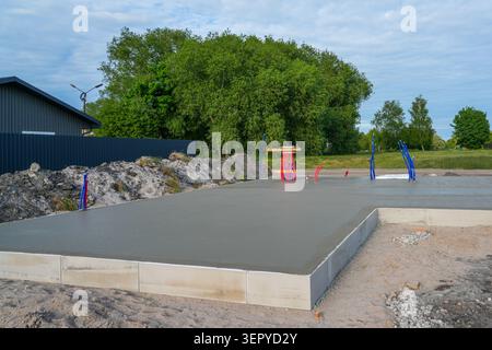 Fresh concrete foundation slab with underfloor heating and utility pipe outputs prepared for residential house construction site Stock Photo