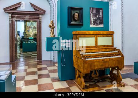 An exhibition space in the DomQuartier in Salzburg, featuring a historical keyboard instrument (early 19th century) as the centrepiece, a wooden figurine and framed portraits on the exhibition wall. The DomQuartier’s tour brings together the art and music history of Salzburg from the Middle Ages to the modern era. Residenzplatz, Salzburg, Austria Stock Photo