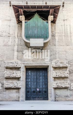 The façade of the Toscaninihof on Max-Reinhardt-Platz in Salzburg, featuring two distinctive design elements: The black entrance portal with Expressionist stone reliefs (below) and the green-patinated external ventilation shaft of the Felsenreitschule (above) mark the interface between the historic rock face and the modern festival complex. Salzburg, Austria Stock Photo