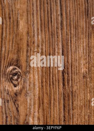 Vertical close-up view of an aged wooden plank showing deep natural grain lines, a prominent knot on the left, and textured surface wear. Warm brown t Stock Photo