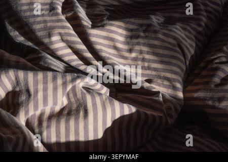 Textured striped fabric in warm light shows soft grooves and folds. The pattern creates a soothing visual effect suitable for textile and interior the Stock Photo