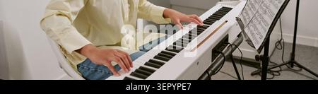 Header of Teenager Playing Digital Piano during Music Lesson at Home Stock Photo