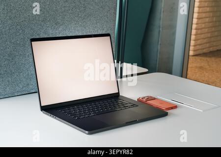 Poznan, Poland, June 13, 2026, Laptop blank mockup screen smartphone desk workspace office business corporate technology. Modern black laptop with an Stock Photo