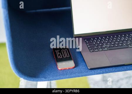 Poznan, Greater Poland, Poland, June 16, 2026, Laptop keyboard open blank screen smartphone digital clock time workspace desk. A modern black laptop w Stock Photo