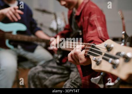 Teenager Playing Bass Guitar during Music Lesson and Practice Stock Photo