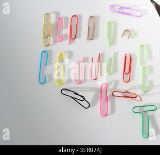 Assorted colorful paper clips arranged on a clean background, practical office stationery for organizing documents, schoolwork and creative projects Stock Photo