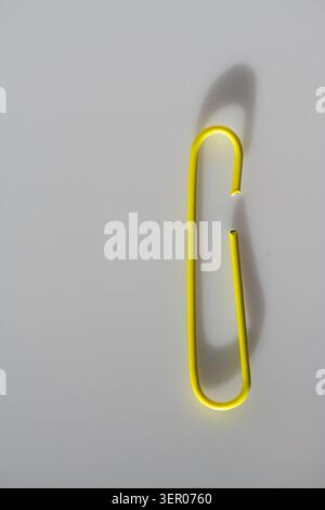Single yellow paper clip isolated on a clean background, a minimal office stationery concept for organization, attachment and simplicity Stock Photo
