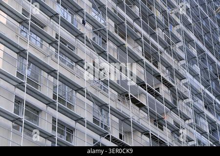 Building facade undergoing renovation with extensive metal scaffolding, providing a framework for access and support during construction, maintenance, Stock Photo