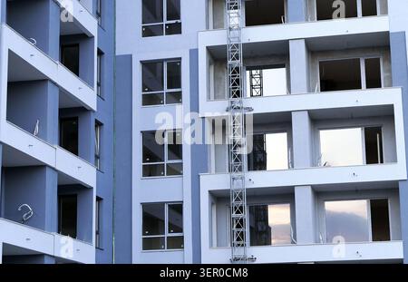 New apartment complex facade featuring balconies and windows during its construction phase, with scaffolding on one side, representing urban developme Stock Photo