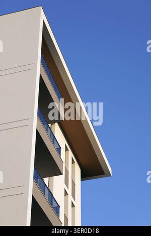 Modern residential building facade featuring clean geometric lines, balconies, and a distinctive roof overhang, creating a striking architectural desi Stock Photo