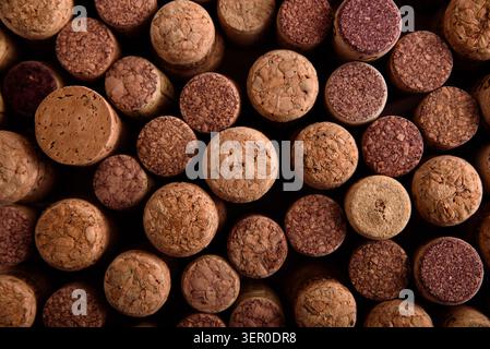 Wine corks with varying textures and red wine stains are tightly packed together, forming an appealing abstract background representing winemaking and Stock Photo