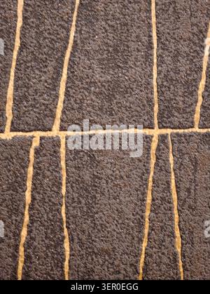 Top-down view of a dense brown rug showing pronounced fiber pile and irregular beige lines forming a loose grid across the surface, with visible shado Stock Photo