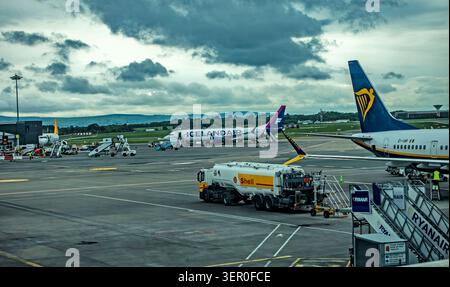 A Shell refueling truck parked on the tarmac near a Ryanair plane and an Icelandair aircraft under cloudy skies at Dublin Airport. Stock Photo
