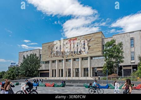 The large mosaic facade of the National Historical Museum under a blue sky at Skanderbeg Square in Tirana, Albania, with people in the plaza. Stock Photo