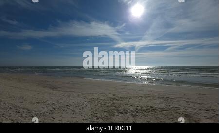 Sun shining over the Baltic Sea with wispy clouds and sandy beach in foreground, Lithuania. Stock Photo