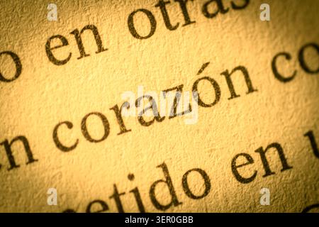 Warm macro photograph of the Spanish word corazon printed on textured paper, with selective focus, golden light and an intimate love concept. Stock Photo
