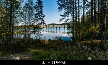Aerial view of two rowing boats on the shore of a calm lake surrounded by a dense forest of pine and birch trees near Konttainen in Kuusamo, North Ost Stock Photo