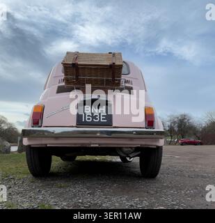Rear view of a pink fiat 500 with a wicker picnic basket & luggage rack in the united kingdom Stock Photo
