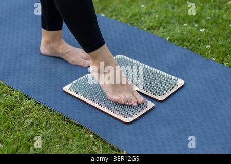 Woman practicing on sadhu board outdoors on yoga mat Stock Photo