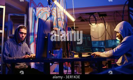 Experienced hacker group members sneaking malware virus on unaware victims computers, stealing sensitive and private information, selling it on internet to highest bidder. Stock Photo