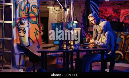 Mischievous hackers in underground bunker using phishing technique that tricks users into revealing sensitive information, cybercriminals stealing passwords from low security systems. Stock Photo