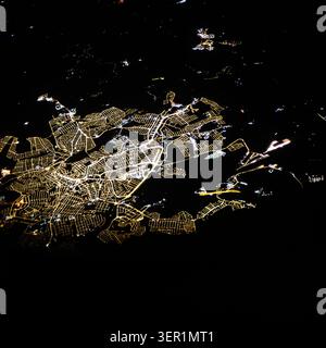 An isolated cluster of city lights surrounded by darkness, creating an abstract pattern that looks like a glowing microchip or futuristic digital data Stock Photo
