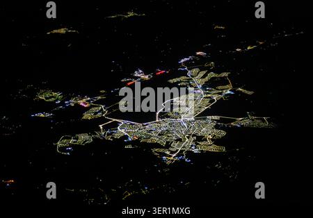 A dramatic aerial view of an isolated urban settlement glowing brightly in the dark night, showing the striking visual footprint of modern human civil Stock Photo