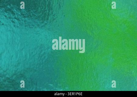 Abstract green and turquoise background with metallic foil texture, resembling abstract sea water surface, macro shot. Stock Photo
