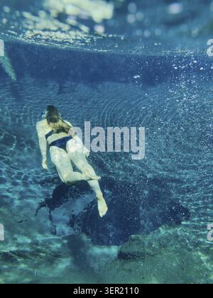 Woman diving to hot spring with clear blue water, underwater shot, Kikuletwa Chemka Hot Springs, Rundugai, Kilimanjaro region, Tanzania Stock Photo