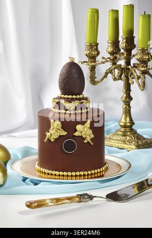 Chocolate easter cake with gold decorations and a chocolate egg on top, creating a luxurious centerpiece for easter celebrations Stock Photo