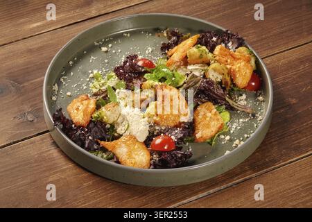 Freshly made caesar salad with grilled chicken, crispy croutons, parmesan cheese, and cherry tomatoes, served on a stylish plate atop a rustic wooden Stock Photo