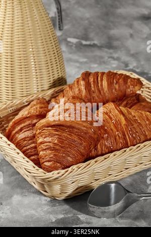 Golden brown croissants sit in a wicker basket, ready to be enjoyed for breakfast or brunch Stock Photo