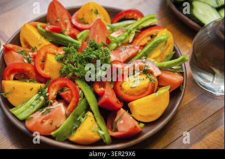 Multi-colored fresh cutted vegetables on a wooden plate Stock Photo