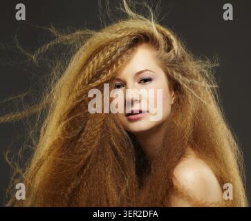 Portrait of young beautiful red-haired woman posing on gray Stock Photo