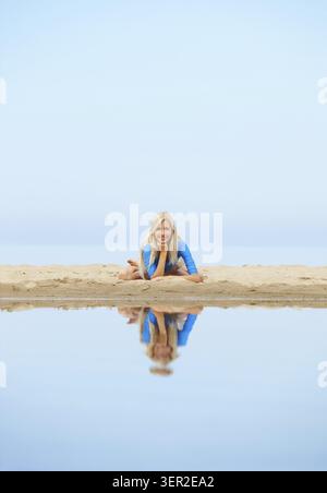 Outdoor portrait of young beautiful blonde woman gymnast posing on the beach Stock Photo