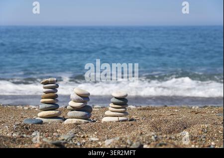 Stack of stones on Petra tou Romiou or Aphrodite Rock Beach, Cyprus. Stones pyramid on pebble beach with sea and blue sky on background Stock Photo