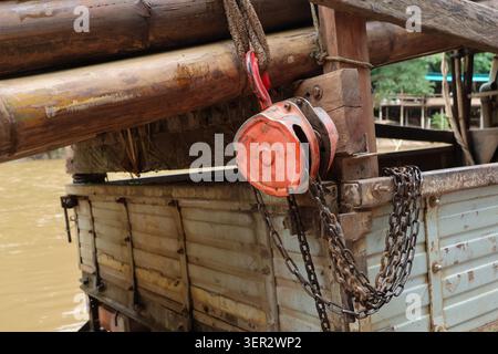 Old metal pulley rusty chain wooden beam and weathered truck bed on riverside industrial and rustic atmosphere outdoor setting vintage equipment natur Stock Photo