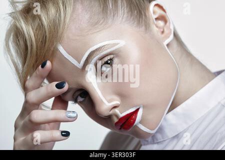Side view of beautiful young woman on gray background. Female with an unusual creative makeup face painting Stock Photo