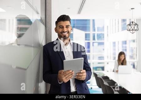 Portrait of confident Indian businessman with tablet standing in workplace Stock Photo