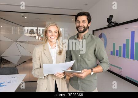 Professional man and woman smiling confidently at camera at workplace Stock Photo