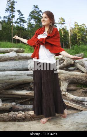 Young pretty woman balancing on logs in the forest Stock Photo
